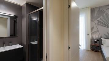 Un bagno moderno con doccia vetrata, uno specchio grande e un lavandino bianco.