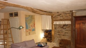 Un salon chaleureux avec une échelle en bois, un canapé, une carte accrochée au mur et un mur en briques.