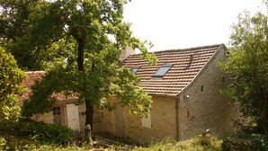 Un bâtiment en pierre avec un toit en pente, une petite fenêtre et une porte.