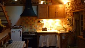 Une cuisine rustique avec des meubles en bois, un plan de travail carrelé, une cuisinière et un évier.
