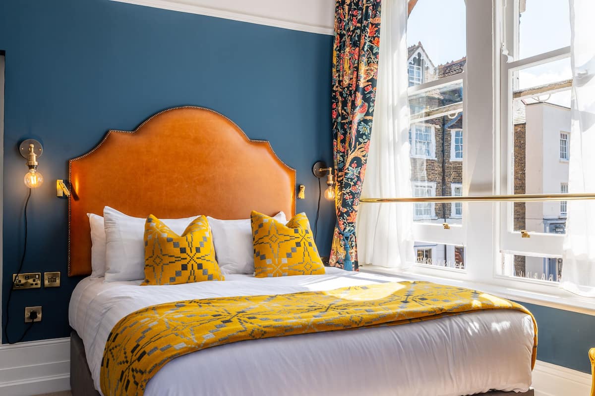 A bed with a wooden headboard, white bedding, and yellow patterned pillows.