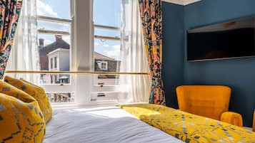 A room with a bed, a window with curtains, a television, and a chair.