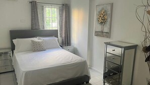 A bedroom with a bed, a nightstand, a dresser, and a window with curtains. - Cozy Central 1-bed Apartment in Kingston (Kingston)