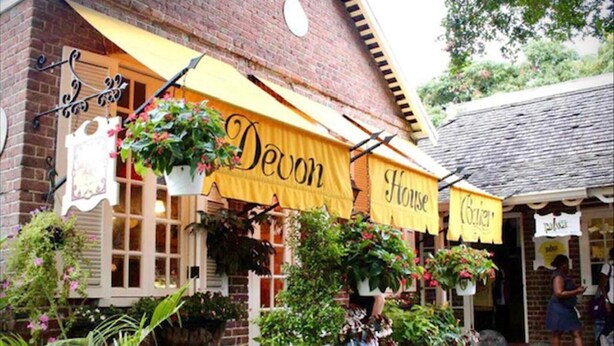 A building with yellow awnings labeled "Devon House" and "Devon". There are hanging plants and a brick facade. - Cozy Central 1-bed Apartment in Kingston (Kingston)