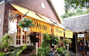 A building with yellow awnings labeled "Devon House" and "Devon". There are hanging plants and a brick facade.