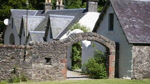 Un arc en pierre mène à une rangée de maisons traditionnelles dotées de toits à pignon et de cheminées.