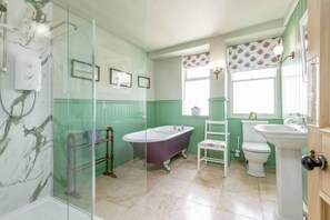 A bathroom with a glass shower enclosure, a freestanding bathtub, a white toilet, and a pedestal sink.