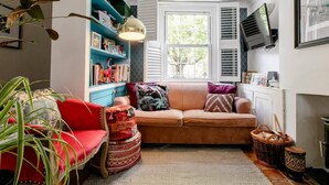 Ein gemütliches Wohnzimmer mit einem roten Sessel, einem beigen Sofa und einem gemusterten Teppich.