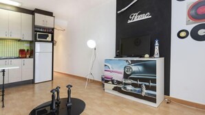Eine moderne Küche mit weißen Schränken, einer Mikrowelle und einem kleinen Esstisch mit Hocker.