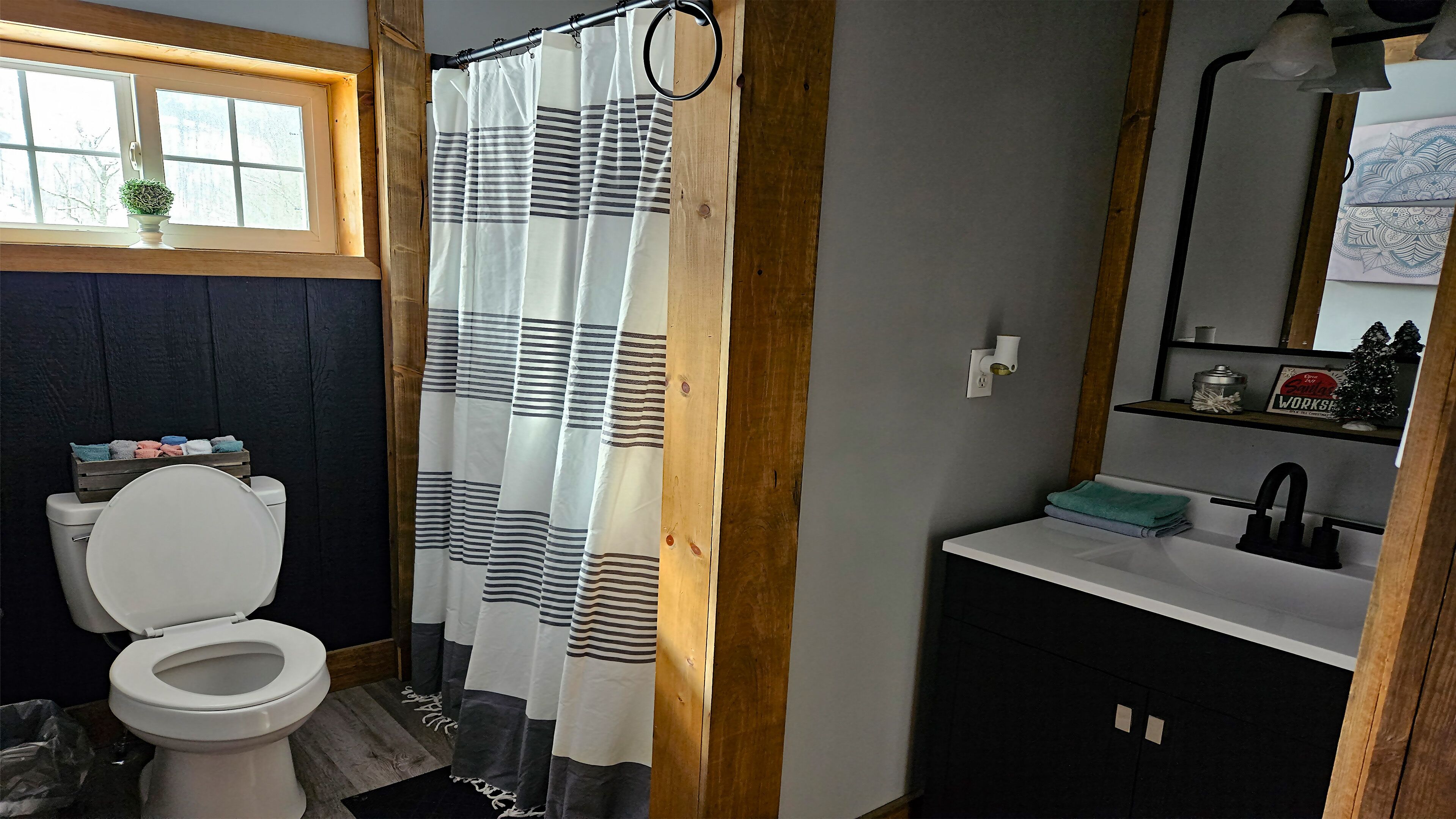 Un baño con inodoro, lavabo, espejo, cortina de ducha y ventana.