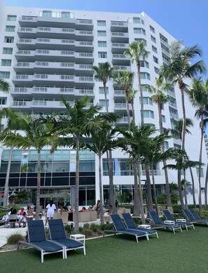 A multi-story hotel with balconies, palm trees, and outdoor seating areas.