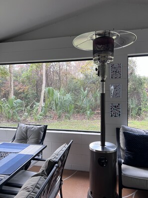 Ein Zimmer mit großem Fenster, einem Tisch mit Stühlen, einem Heizgerät und Wandbildern.