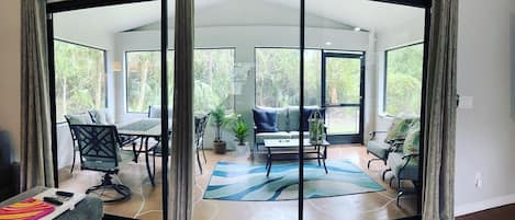 A modern living room with a curved glass door leading to an outdoor area, furnished with a sofa, chairs, and a coffee table.