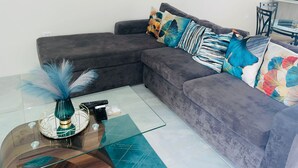 A modern living room with a grey sectional sofa, a glass coffee table, and decorative pillows. - Free Beach&pool Access -vaes Luxury Escape (Discovery Bay)