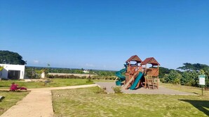 A playground with slides and climbing structures, surrounded by a grassy area and a building. - Free Beach&pool Access -vaes Luxury Escape (Discovery Bay)