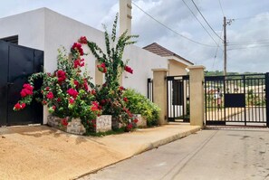 A residential building with a gated entrance, a concrete pathway, and a garden with red flowers. - Free Beach&pool Access -vaes Luxury Escape (Discovery Bay)