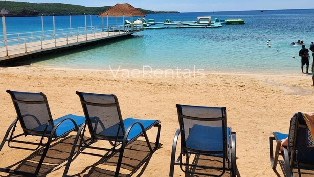 A beach with lounge chairs and a pier extending into the water. - Free Beach&pool Access -vaes Luxury Escape (Discovery Bay)