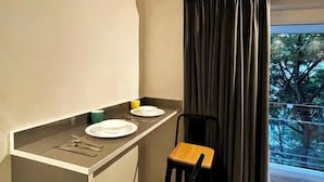 Un rincón comedor compacto con una mesa pequeña, dos sillas y un ventanal con cortinas.