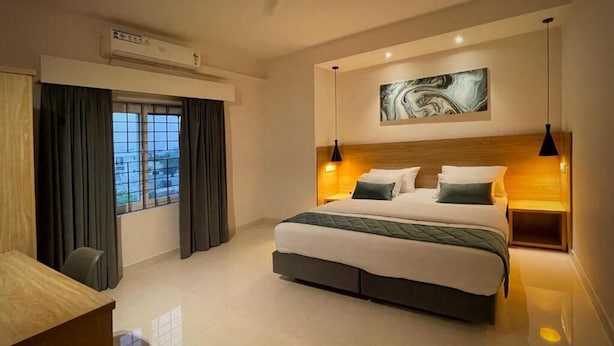 Una habitación de hotel moderna con una cama grande, un escritorio y un ventanal con cortinas.