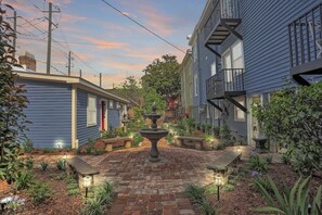 A courtyard with a central fountain, surrounded by brick pathways and small plants.