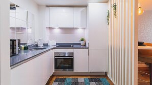 Una cucina moderna con mobili bianchi, forno integrato e piano di lavoro nero.