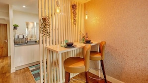 Una cucina moderna con un divisorio in legno, un tavolo da pranzo con due sedie e un lampadario.