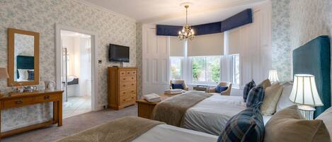 Une chambre d’hôtel avec deux lits, une commode, un téléviseur et une fenêtre donnant sur un paysage verdoyant.