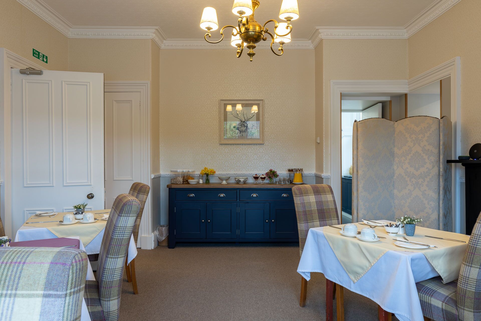 A dining area with a chandelier, a fireplace, and a painting on the wall.