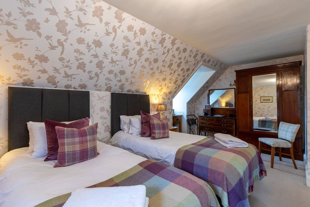 A bedroom with two beds, a dresser, a chair, and a mirror.