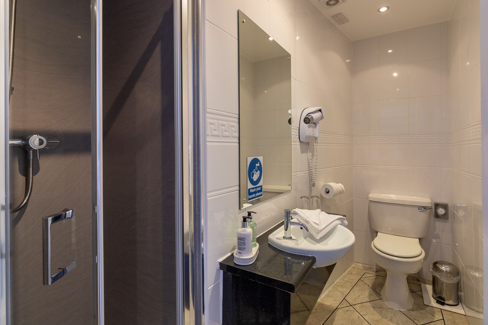 A modern bathroom with a glass shower enclosure, a sink with a mirror, and a toilet.