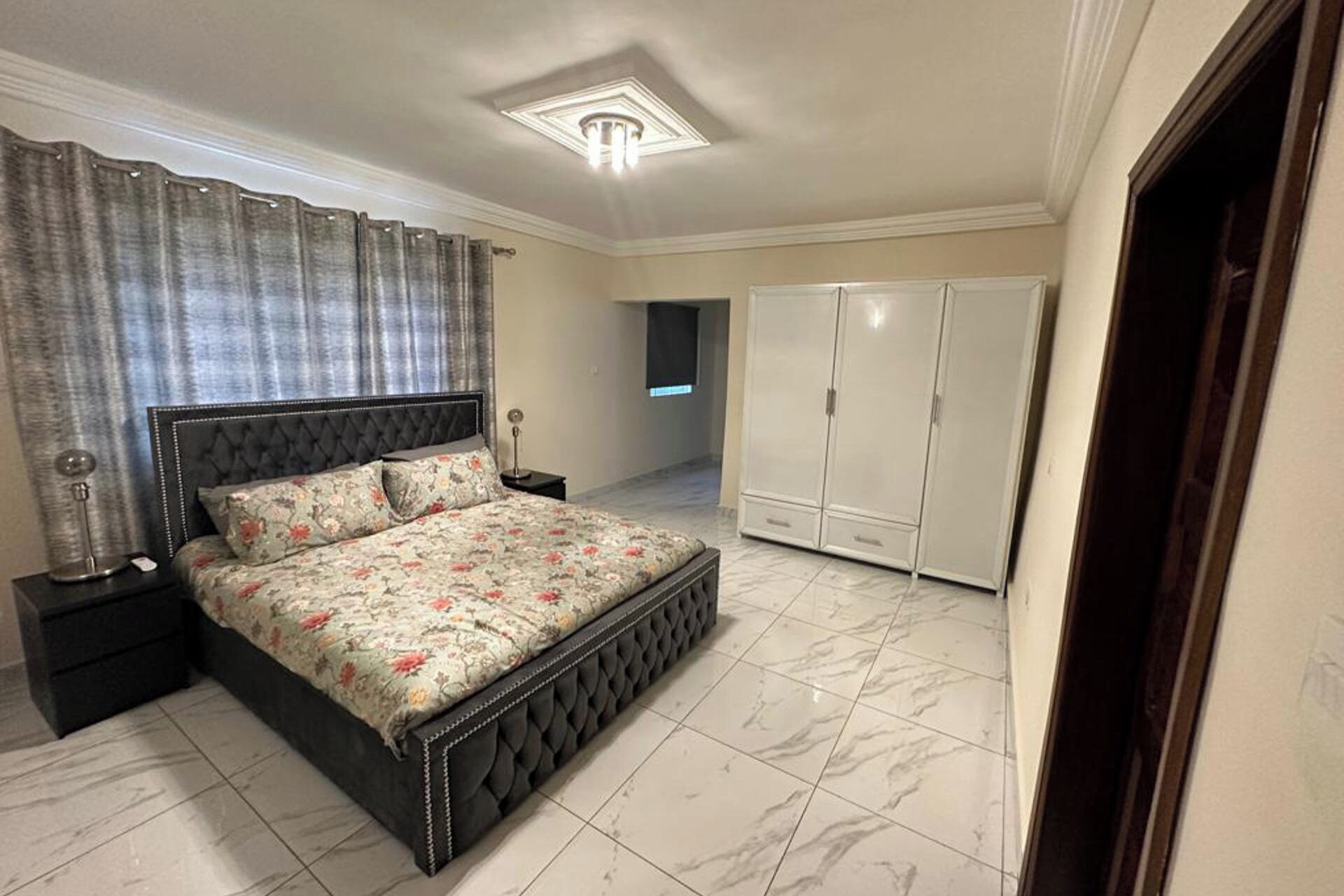 A bedroom with a large bed, a wardrobe, and a nightstand.