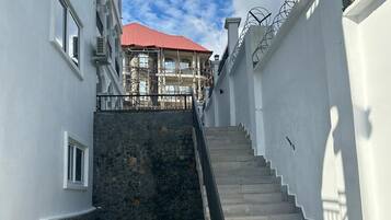 A staircase leading to a building with a red roof, surrounded by white walls and a stone base.