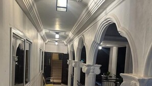 A corridor with white columns, a bench, and a railing. - 3 Bed Apartment Sleeps 6 - Ensuites, Parking, Wifi (Freetown)