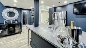 Een moderne keuken met een inbouwkoelkast, een roestvrijstalen spoelbak en een bar voorzien van glazen en een champagnekoeler.