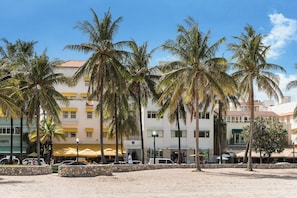 Um hotel à beira-mar com palmeiras, uma praia arenosa e um céu azul límpido.