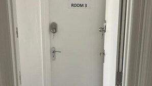 A hallway leading to a door labeled "ROOM 3" with a doorbell and a keyhole.