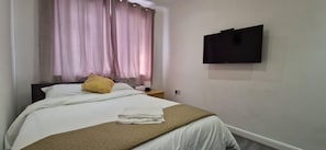 Relax in a cozy retreat with a comfortable bed, bedside table, and flat-screen TV.