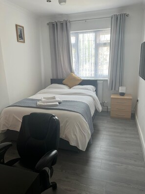 Cozy retreat with a neatly made bed, bedside table, and comfortable chair.