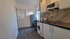 A compact kitchen with a washing machine, a microwave, and a sink.