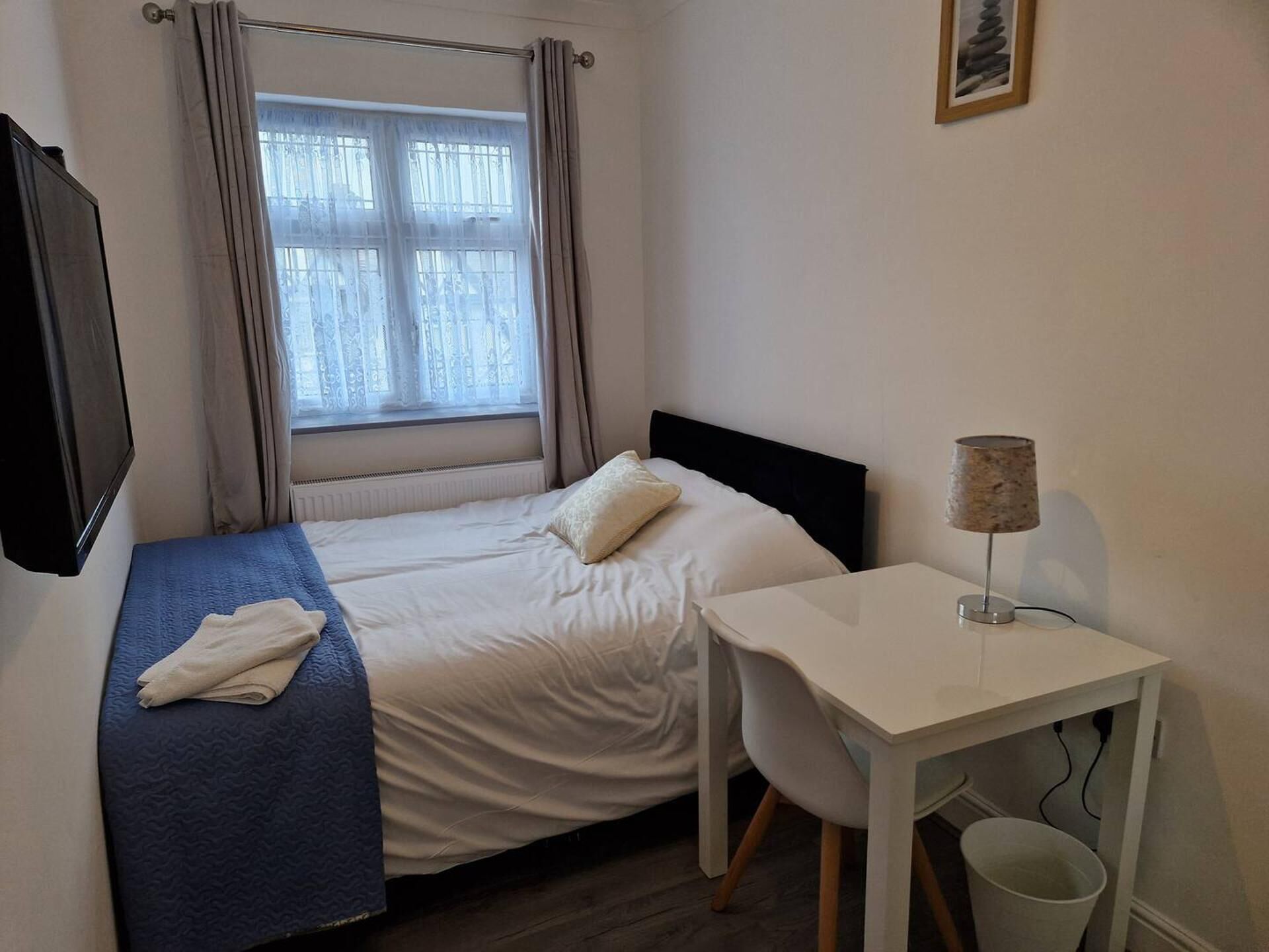 Ein kleiner, ordentlicher Raum mit einem Bett, einem Schreibtisch und einem Stuhl.