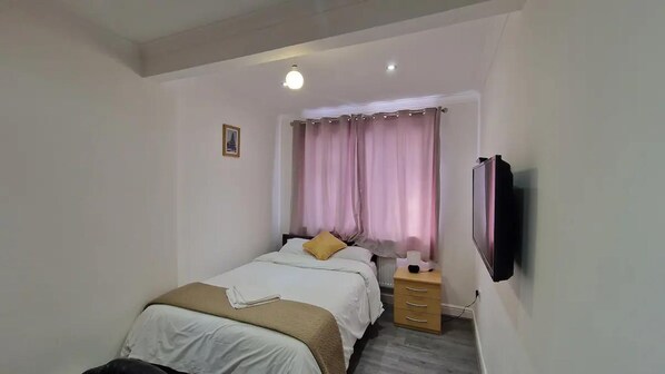 Cozy retreat with a single bed, bedside table, and TV.