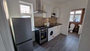 A compact kitchen with a refrigerator, stove, microwave, and washing machine.