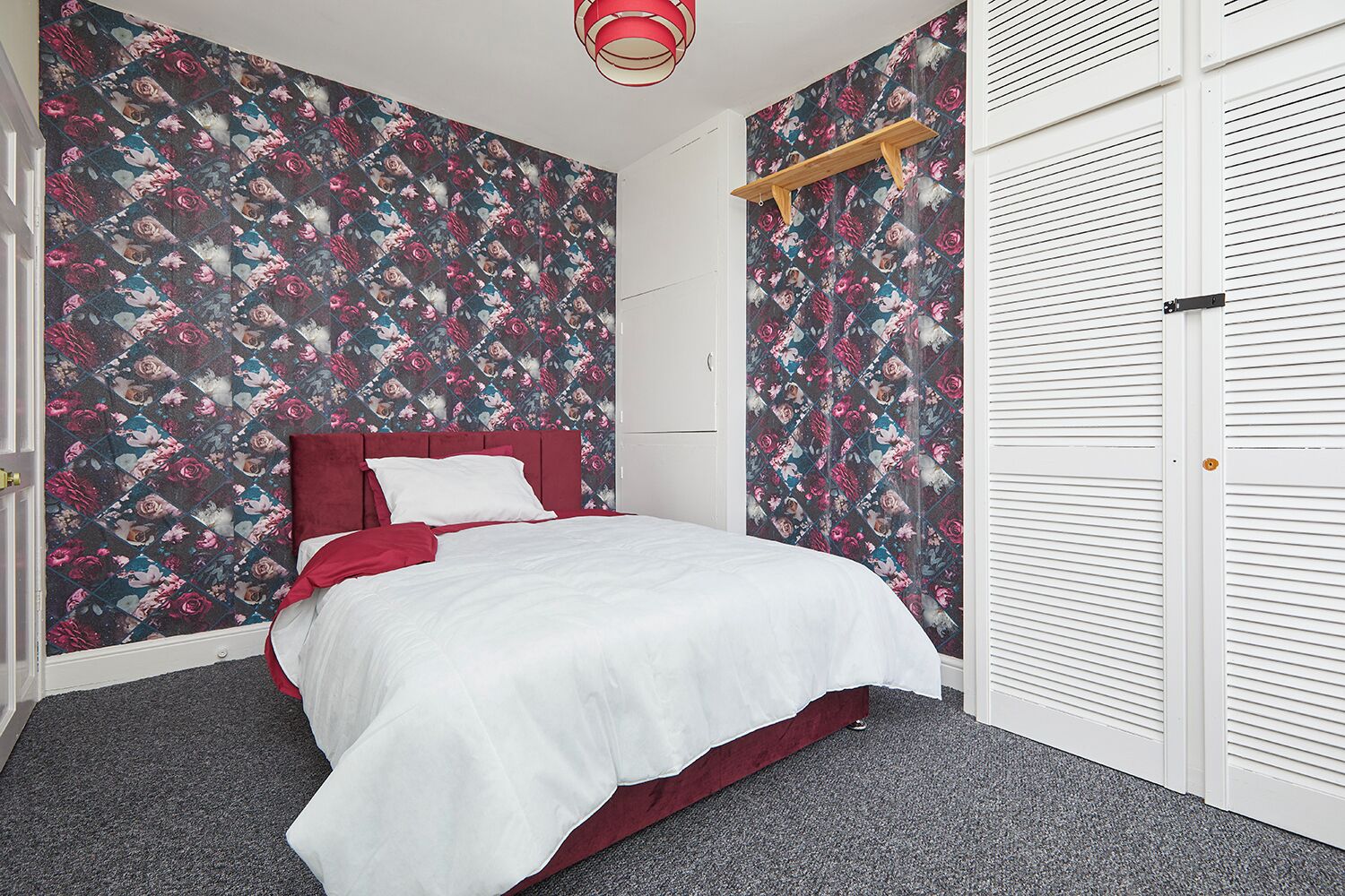Une chambre à coucher avec un lit, une armoire et un mur décoré de motifs floraux.