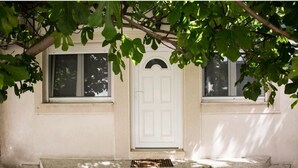 Una casa con puerta blanca, dos ventanas y un porche de hormigón.