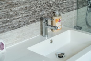 A bathroom sink with a chrome faucet, a soap dispenser, and a drain.