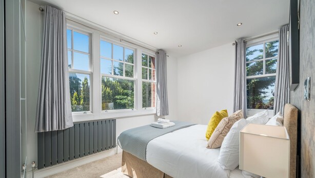 Une chambre à coucher avec un lit, une table de chevet et une fenêtre avec des rideaux.
