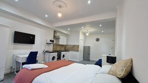 Une chambre d’hôtel moderne équipée d’un lit, d’un bureau, d’une machine à laver, d’un four à micro-ondes et d’une télévision.