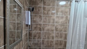 Une salle de bain avec une douche, un miroir et une baignoire.