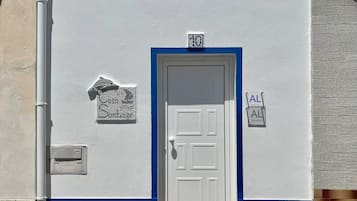 A building with a white and blue facade, a white door, and a small window.