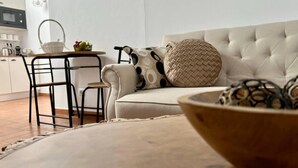 A modern living room with a sofa, a dining table with chairs, and a kitchen area in the background. - Casa Santiago & Mafalda Lux Home in Olhao, Algarve (Olhao)